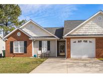 Charming home with a brick and siding exterior, a two-car garage and a well-maintained front yard at 204 Edinburgh Ct, Mount Holly, NC 28120