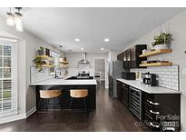 Modern kitchen featuring dark cabinets, a large island with seating, and stainless steel appliances at 7201 Brassy Creek Ln, Charlotte, NC 28269