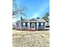 Charming single story home with mature trees, grey siding, blue shutters, and a well maintained yard at 502 Memorial Dr, Clover, SC 29710