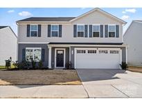 Charming two-story home featuring a two-car garage, gray siding and dark shutters at 668 Pointe Andrews Sw Dr # 93, Concord, NC 28025