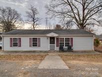Charming single-story home with light siding, red shutters and covered front porch at 709 High St, Albemarle, NC 28001