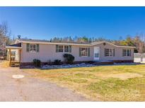 Charming single-story home with a well-maintained lawn, a long driveway, and mature trees at 1020 John Miller Rd, Rockwell, NC 28138