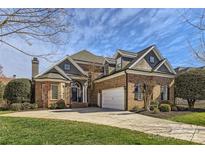 Charming brick home featuring an attached garage, well manicured lawn, and a classic roofline at 16212 Walcot Ln, Cornelius, NC 28031