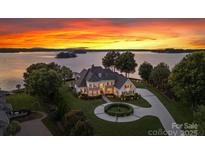 Stunning lakefront estate with lush landscaping, circular drive, and breathtaking sunset views at 2477 Peninsula Shores Ct, Denver, NC 28037