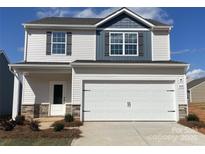 Two-story home featuring vinyl siding, a garage, and a covered front porch with stone accents at 3430 Saddlebred Dr, Gastonia, NC 28052