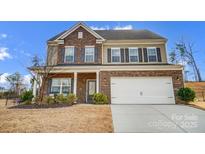 Charming two-story home featuring a brick facade, two-car garage, and well-manicured lawn at 9325 Beecroft Valley Dr, Huntersville, NC 28078