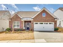 Charming red brick home featuring a two-car garage, manicured lawn, and complementary landscaping at 10014 Berkeley Castle Dr, Charlotte, NC 28273