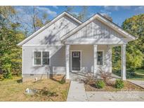 Charming home featuring a covered front porch with white columns and vertical siding at 1006 W B St, Kannapolis, NC 28081