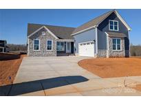 Charming exterior showcasing stone accents, blue siding, and a spacious driveway leading to a two-car garage at 1945 Hendricks St, Rock Hill, SC 29732