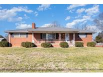 Charming brick ranch-style home featuring a covered front porch and manicured landscaping at 290 S Enochville Ave, Kannapolis, NC 28081