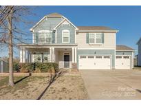 Charming two-story home featuring a three car garage, covered porch and a combination of siding and stone at 5024 Grace View Dr, Pineville, NC 28134