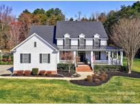 Charming two-story home featuring a covered front porch, manicured lawn, and beautiful landscaping at 8817 Kerns Meadow Ln, Huntersville, NC 28078