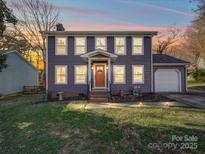 Charming two-story home featuring gray siding, a bright orange front door, and a well-maintained lawn at 10929 Lassen Ct, Charlotte, NC 28214