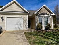 Charming single-story home featuring tan siding, well-kept lawn, and an attached two-car garage at 12411 Twelvetrees Ln, Huntersville, NC 28078