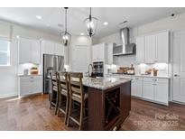 A spacious kitchen featuring white cabinetry, stainless steel appliances, a large island, and modern pendant lighting at 126 Goorawing Ln, Mooresville, NC 28115