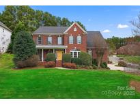 Charming two-story red brick home with manicured lawn and lush landscaping at 204 Silvercliff Dr, Mount Holly, NC 28120