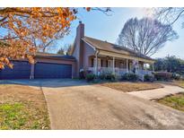 Charming home featuring a two-car garage, brown siding, inviting front porch, and well-maintained landscaping at 210 Keltic Meadows Dr, Gastonia, NC 28056
