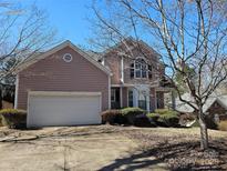 Two-story home with light pink siding, an attached garage, and a driveway lined with shrubbery at 3016 Pennridge Pl, Matthews, NC 28105