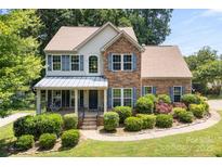 Charming two-story home boasts manicured landscaping, stone accents, and inviting covered front porch at 329 Squirrel Ln, Clover, SC 29710