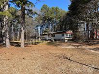 Exterior view of home with car port and surrounded by trees in a wooded area at 1406 Ratchford Dr, Dallas, NC 28034