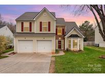 Charming two-story home featuring a two-car garage, red shutters, and a well-manicured lawn at sunset at 1452 Deer Forest Dr, Indian Land, SC 29707