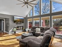 Bright living room with hardwood floors, cathedral ceiling, large windows, fireplace and a modern sectional sofa at 506 Coolidge Ct, Statesville, NC 28677