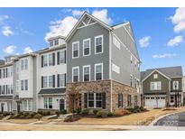 Beautiful townhome featuring a brick facade, gray siding, and black shutters against a backdrop of a blue, partly cloudy sky at 1037 Naples Dr, Davidson, NC 28036