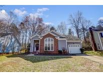 Charming home with large front window, brick accent, attached garage, and well maintained lawn at 11010 Pale Hickory Ln, Charlotte, NC 28215