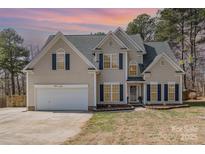 Charming two-story home featuring neutral siding, black shutters, and an attached two-car garage at 148 Painted Bunting Dr, Troutman, NC 28166