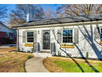 Charming painted brick home with black door, gray shutters and flower boxes under the windows at 1865 Woodland Dr, Charlotte, NC 28205