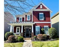 Charming two-story home featuring a red exterior, covered porch, and well-maintained landscaping at 10234 Elizabeth Crest Ln # 147, Charlotte, NC 28277