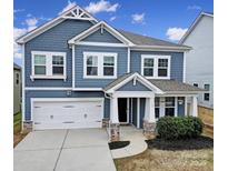 Charming two-story home featuring a white garage door, stone accents, and a covered front porch at 112 Morgans Branch Rd, Belmont, NC 28012