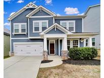 Charming two-story home featuring a blue exterior, covered porch, attached garage, and landscaped front yard at 112 Morgans Branch Rd, Belmont, NC 28012