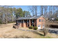 Charming two-story brick home features a covered porch, attached garage, and mature trees at 118 Sunset Dr, Chester, SC 29706