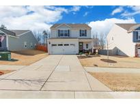 Charming two-story home featuring a wide driveway, attached garage, and manicured landscaping at 147 Colonial Reserve Ave, Troutman, NC 28166