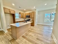 Modern kitchen with an island, stainless steel appliances, and wood-look flooring at 613 Granite Ave, Gastonia, NC 28052