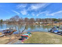 Expansive lake view featuring a dock, boat lifts, and canoes on a sunny day with blue skies and scattered clouds at 107 Pier 33 Dr # 103, Mooresville, NC 28117