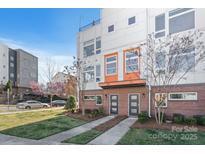 Modern townhome with brick facade, landscaped lawn, and stylish doors, offering a contemporary living space at 107 W Poindexter Dr, Charlotte, NC 28203