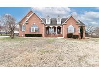 Charming brick home featuring a covered porch, dormer windows, and a well-manicured lawn at 123 Wheatridge Dr, Statesville, NC 28625