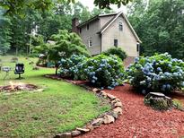 Inviting backyard featuring a cozy fire pit and meticulously landscaped garden with vibrant hydrangea bushes at 1496 Givens St, Hickory, NC 28602