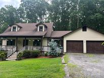 Charming home featuring a covered front porch, dormer windows, attached 2-car garage and mature trees at 1496 Givens St, Hickory, NC 28602