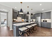 Modern kitchen with gray cabinetry, stainless steel appliances, and a large center island with seating at 3009 Tramore Dr, Harrisburg, NC 28075