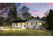 Charming, single-story home with white painted brick, dark shutters, well-maintained lawn, and walkway lighting at 4913 Seacroft Rd, Charlotte, NC 28210
