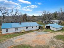 Charming home with a blue roof and a detached garage, set on a spacious lot with mature trees at 836 Love Rd, Blackstock, SC 29014