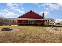 Charming red home featuring a covered porch and a stone fire pit in the front yard at 223 Scottish Dr, Mooresville, NC 28115