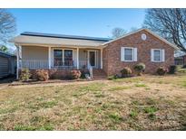 Charming brick and siding home with a cozy front porch, solar panels, and well-manicured landscaping at 9026 Longview Dr, Charlotte, NC 28214