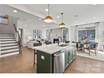 Open-concept kitchen with island, stainless steel appliances, and view into the living room with fireplace at 13308 Chopin Ridge Rd, Huntersville, NC 28078