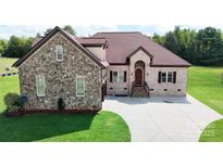A charming home featuring a combination of stone and brick, a large driveway, and lush green grass at 1974 Glen Manor Ct, Lincolnton, NC 28092