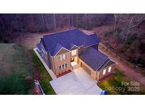Stunning aerial view of a two-story brick home with an attached garage and a paved driveway at 2302 Rayecliff Ln, Charlotte, NC 28214