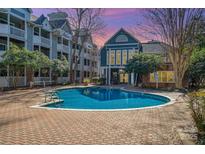 Community pool with a brick surround and several apartment buildings in the background at 525 N Graham St # 3B, Charlotte, NC 28202